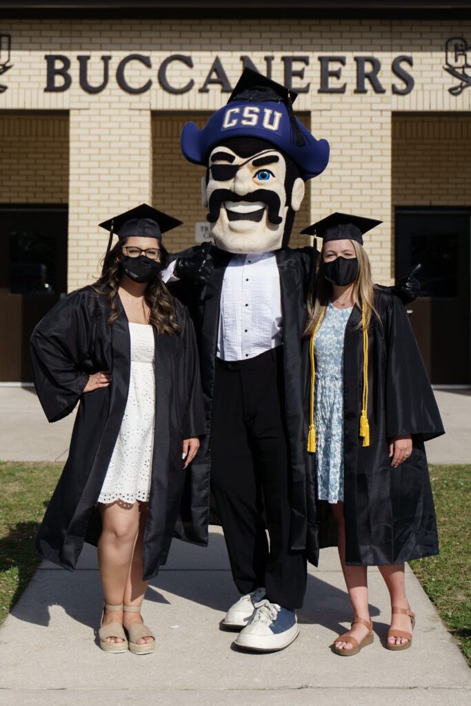 Two graduates from Charleston Southern University pose with Bucky before Commencement 2021