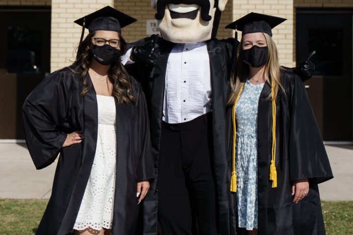 Two graduates from Charleston Southern University pose with Bucky before Commencement 2021