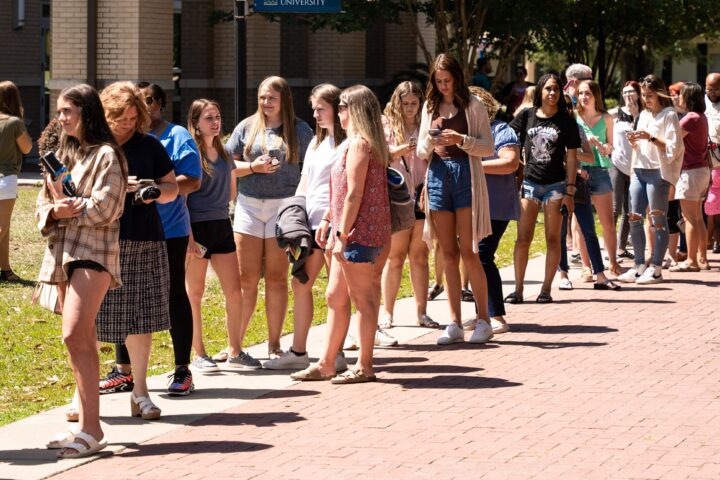 Multiple students on campus are in a line to enter chapel for a student orientation