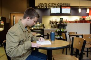 A student in Java City reading with a cup of coffee.