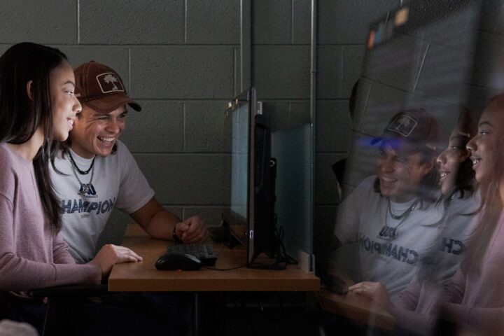 Two students looking at a computer screen in a dark room.