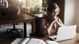Young woman in glasses using laptop for her online degree program.