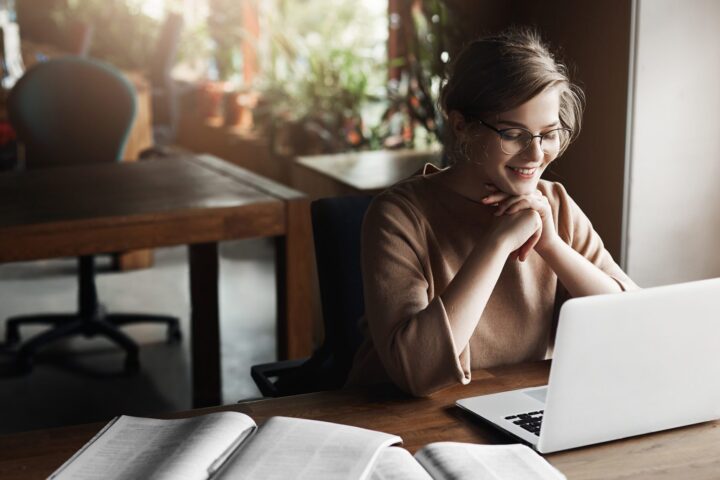 Young woman in glasses using laptop for her online degree program.