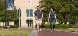 Two students walking down a brick path on CSU's campus with the science building in the background.