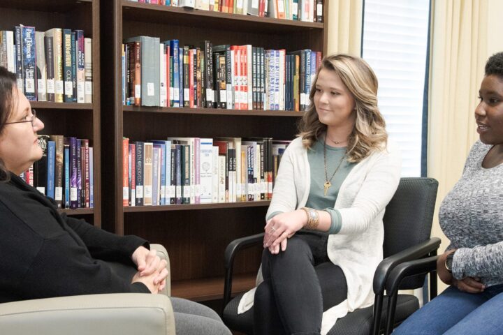 Two students sitting with an couselor peacefully in discussion.