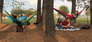 Students hanging in their Eno hammocks in a wooded section of campus.