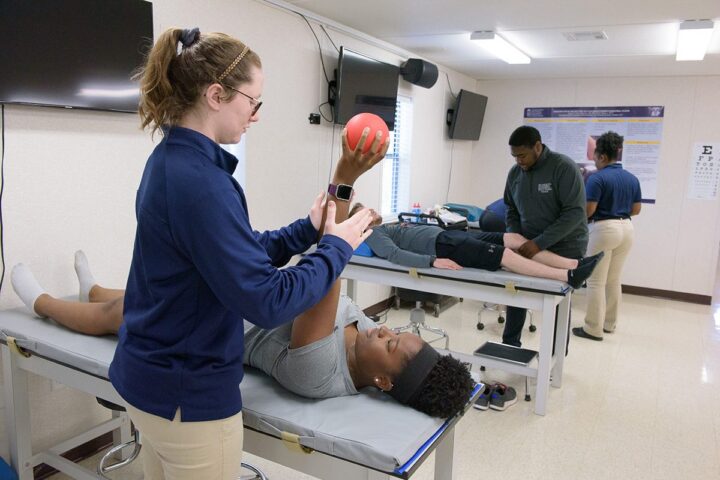 Athletic training students working on other students in a classroom lab.