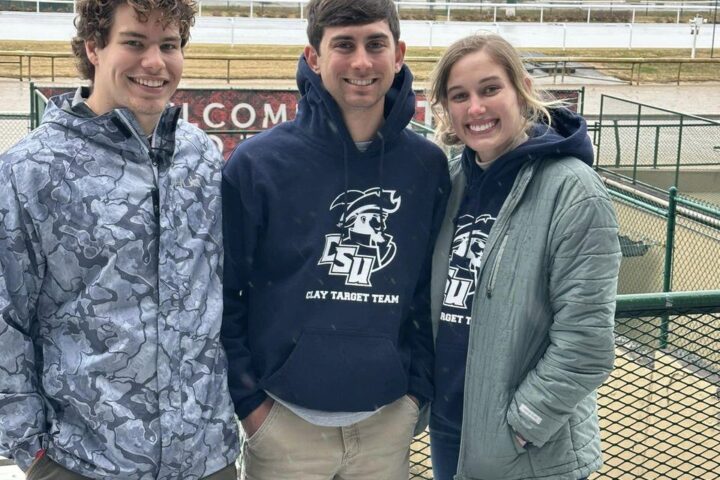 Two boys and one girl from the Clay Target Team smiling for a group picture.
