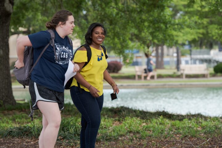 Two students walking around the reflection pond at CSU while on their was to class.