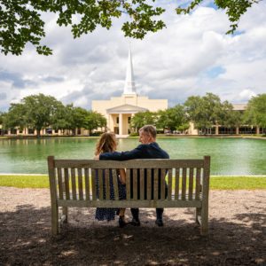 Dr. Costin and his wife sitting on a bench next to the point and in front of chapel