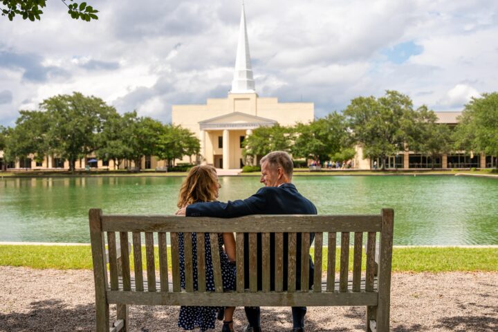 Dr. Costin and his wife sitting on a bench next to the point and in front of chapel