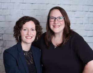 Dr. Hinson and Dr. Donnelly smiling on the picture, a white wall in the background