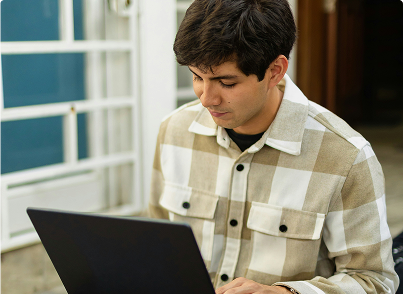 Male student in checkered shirt uses laptop