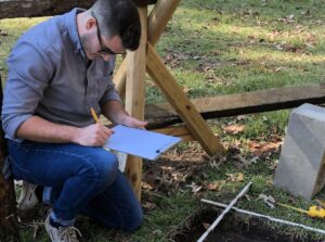 Ethan Shuler documents layout of new dig site in internship