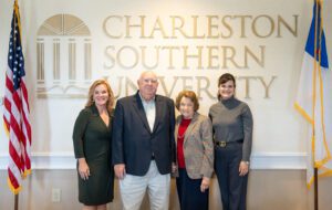 Four people taking a picture between two flags and CSU in the background