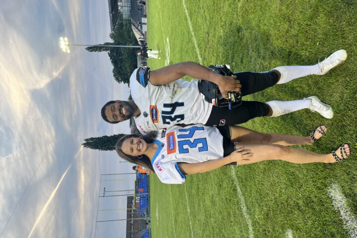 A girl and boy smiling in their football costume number 34 on the football field