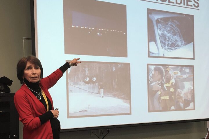 Coroner Rae Wooten at Charleston Southern pointing to images on a projection screen.