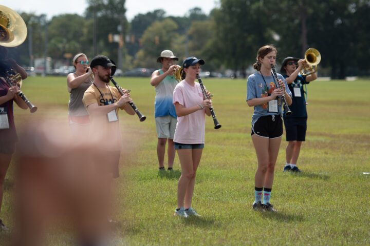 A Marching band praciting outside on the grass